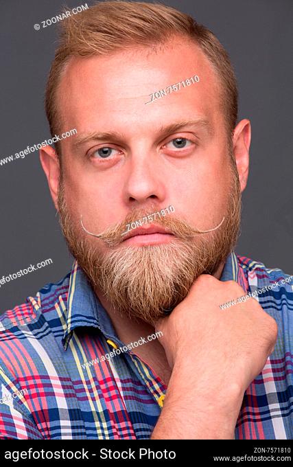 Portrait of handsome bearded man. Serious mature blond man posing for photographer and keeping his blond beard