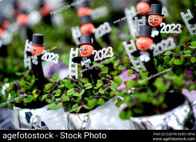 PRODUCTION - 21 December 2022, Lower Saxony, Weener: Numerous clover plants with a small chimney sweep and the year ""2023"" stand on a transport cart in a...