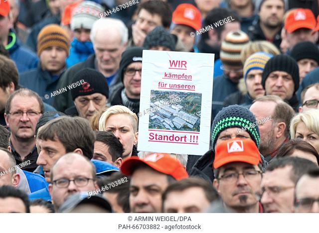 A man holds up a sign that reads 'WE will fight for our plant!!!' as Siemens employees attend a rally held against the planned job cuts at the Siemens plant in...