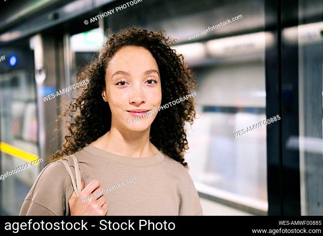 Smiling woman with curly hair at subway station