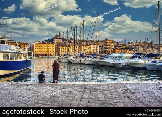 two men at the old port with Notre-Dame de la Garde Basilica, Marseille, France