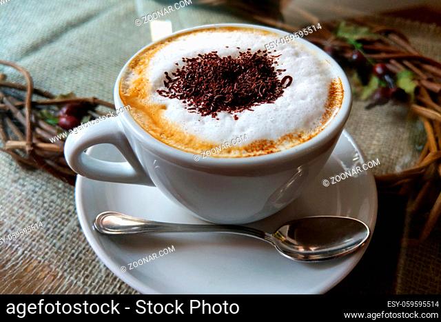 A cup of coffee in a white cup on wooden background
