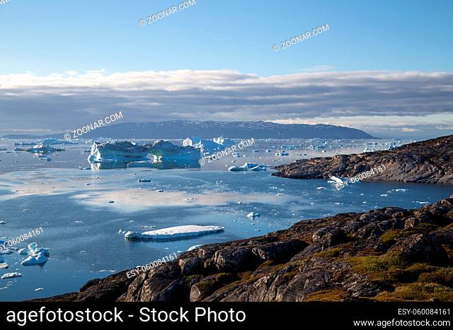 Ilulissat, Greenland - July 9, 2018: The coastline and icebergs during midnight sun. Rodebay, also known as Oqaatsut is a fishing settlement north of Ilulissat