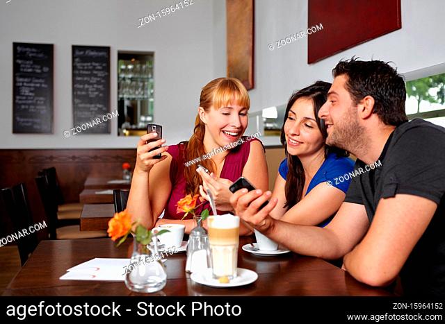 Lachende Gruppe spielt mit ihren Handys im Restaurant
