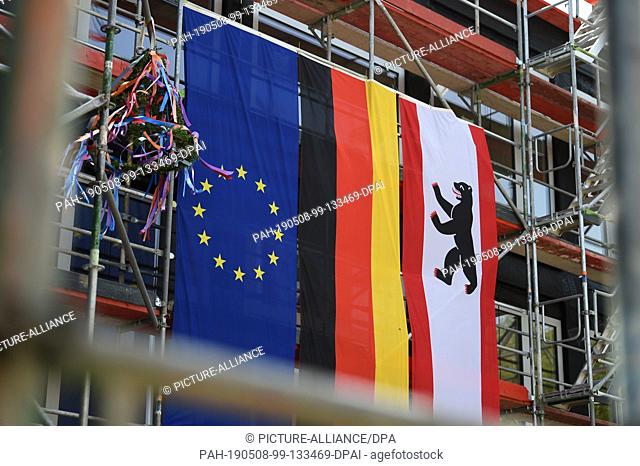 08 May 2019, Berlin: A topping-out wreath as well as the European, German and Berlin flags hang on a school building in Berlin-Lichtenberg