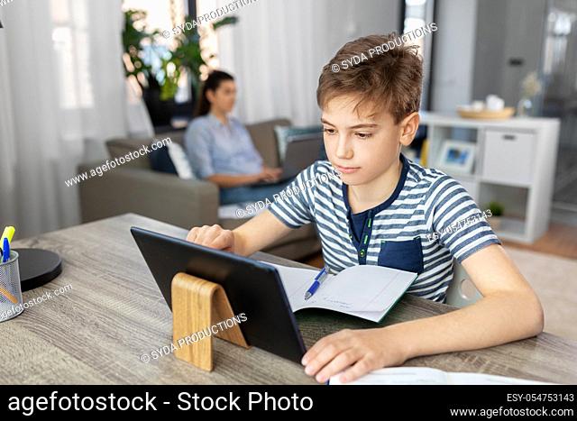 student boy with tablet computer learning at home