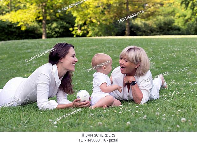 Grandmother with mother and granddaughter (12-17 months) playing on grass
