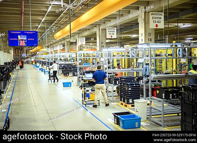 25 July 2023, Lower Saxony, Winsen (Luhe): Employees use scanners to pack goods into suitable shipping packages at the Amazon Logistik GmbH logistics center in...