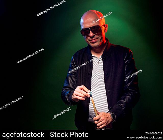 Trendy man in dark glasses and playing pool lining up on the cue ball with his cue as he prepares to shoot in a dark pub or club