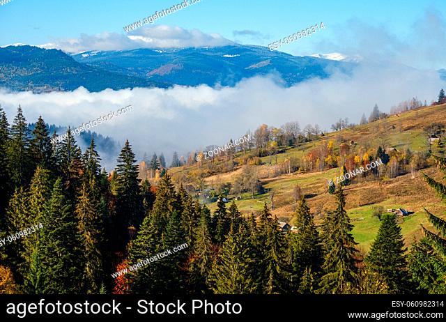 Late autumn mountain morning scene with snow covered tops in far and foggy clouds in valleys. Picturesque traveling, seasonal