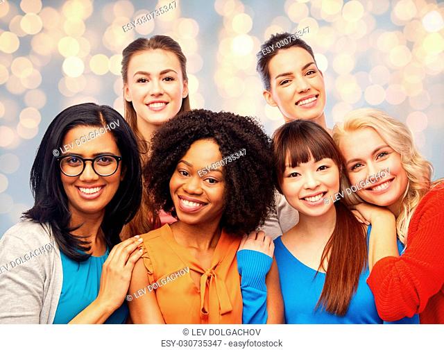 diversity, ethnicity and people concept - international group of happy smiling different women hugging over holidays lights background