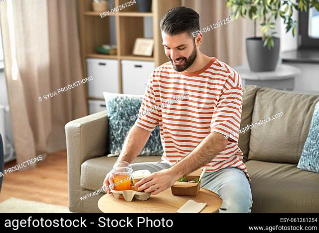 smiling man with takeaway food and drinks at home