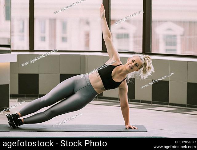 Woman working out on a mat doing a side plank; Wellington, New Zealand