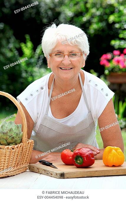 Closeup of elderly woman in garden with basket of fresh vegetables