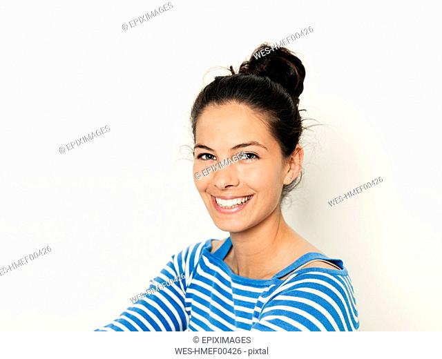 Beautiful young woman with black hair and blue white striped sweater is posing in front of white background
