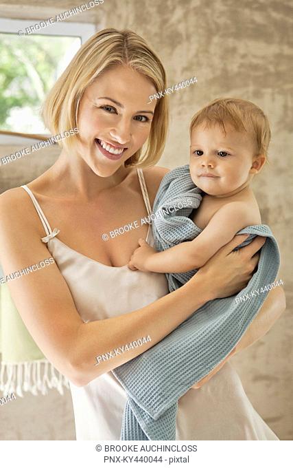Smiling woman holding her baby in towel
