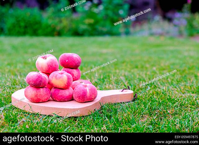 Saturn peach on a serving board in the garden
