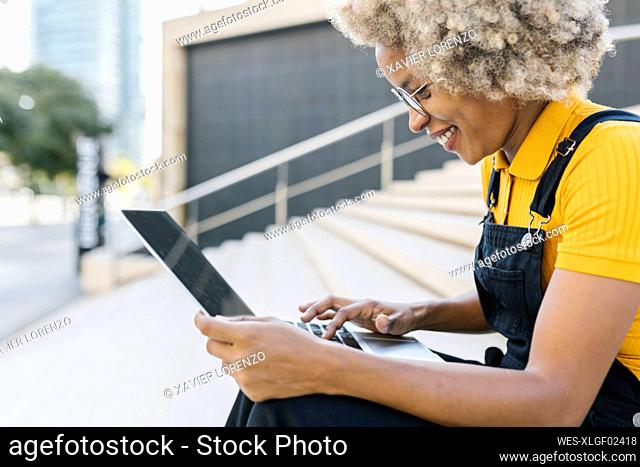 Smiling woman using laptop on steps
