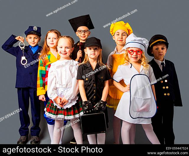 Happy friends dressed as doctor, cook, judge, policeman, agent and singer. Little kids dressing up as professions. Future education concept