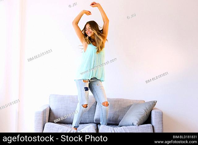 Mixed race woman jumping on sofa