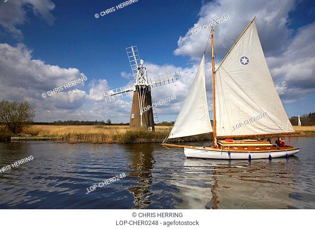England, Norfolk, Turf Fen, A traditional wooden sailing boat sailing in front of Turf Fen windmill on the River Ant
