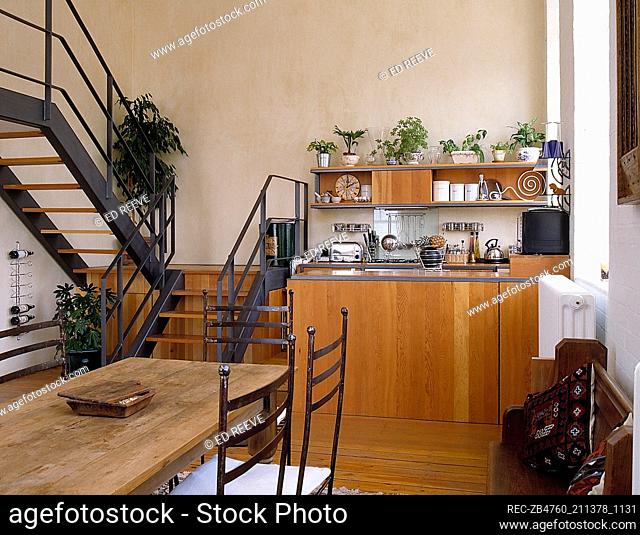 Wooden dining table in open plan kitchen diner area with staircase
