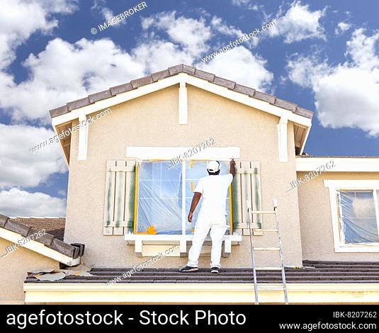 Busy house painter painting the trim and shutters of A home