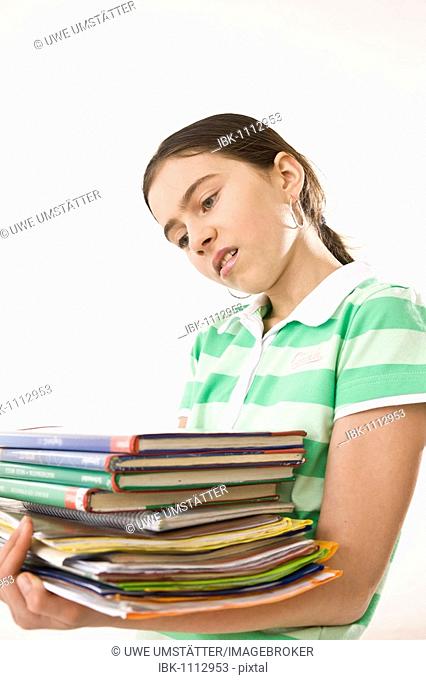 Irritated girl carrying a pile of exercise books and school books
