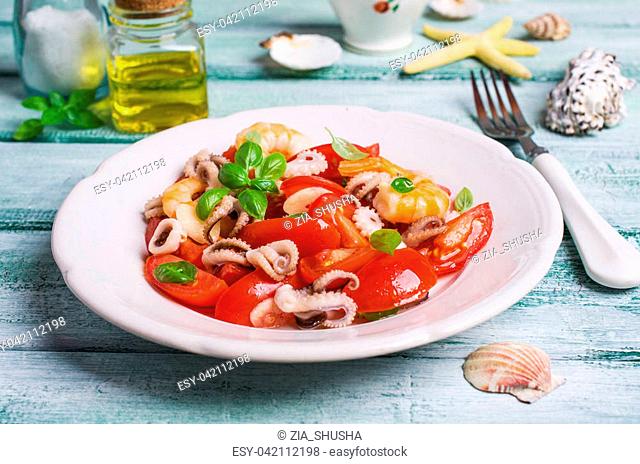 Salad with seafood and vegetables in a plate on the table. Selective focus