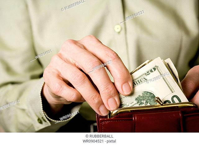 Mid section view of a woman keeping paper currency in a purse