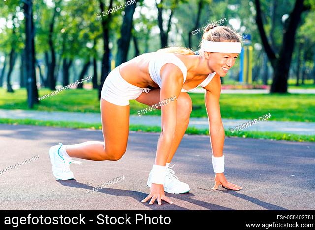 Young woman runner outdoor standing in start pose