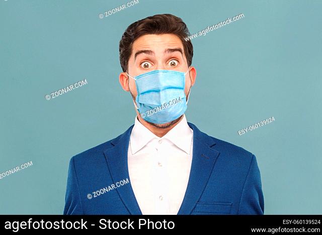 Closeup portrait of surprised or shocked young man with surgical medical mask looking at camera with big eyes. Business people medicine, health care concept
