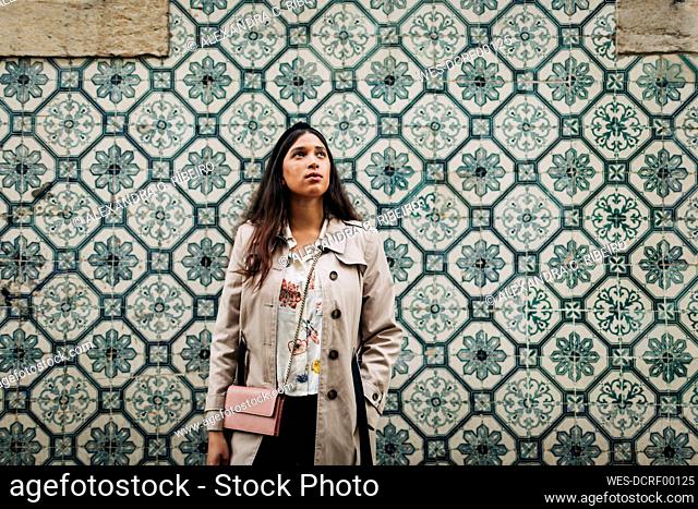 Portugal, Lisbon, Young traveller looking up and standing at a wall with typical Portuguese tiles