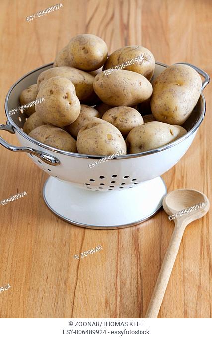 White Enamel Colander with raw potatoes