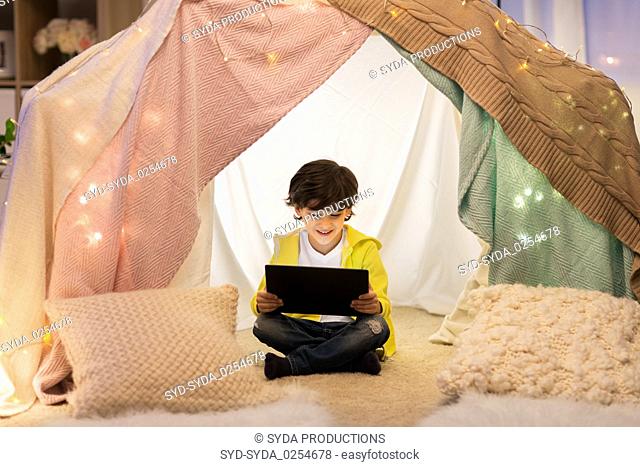 little boy with tablet pc in kids tent at home