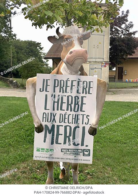 Picture of a cardboard holder in the shape of a cow holding a sign with the text ""I'd rather eat something green instead of trash""