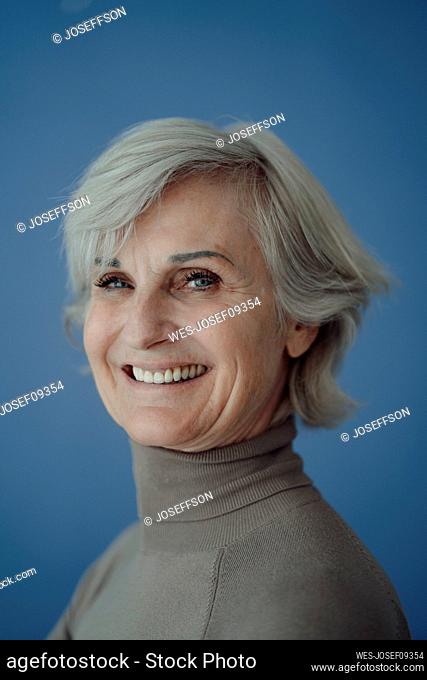Happy senior woman with gray hair against blue background