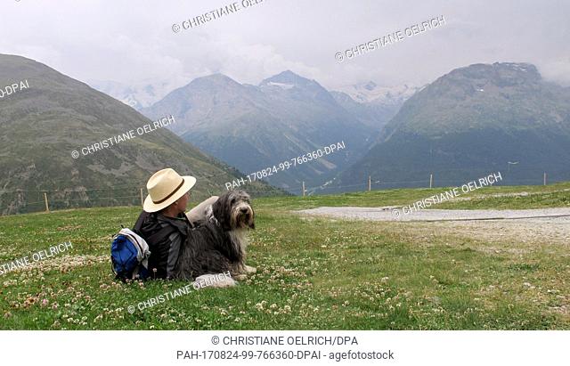A hiker and his dog resting in Muottas Muragl - a good 2500 meters high - in the canton of Graubunden, Switzerland, 20 July 2017