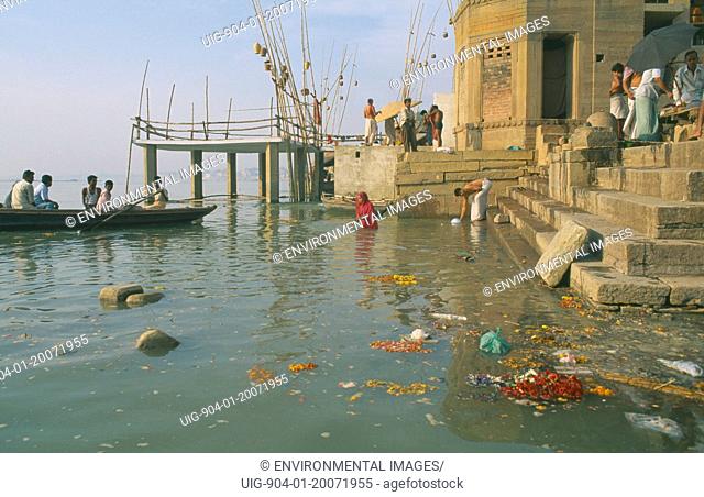 INDIA Uttar Pradesh Varanasi. Scum and remnants of flower offerings float around the steps of the ghats on the River Ganges.