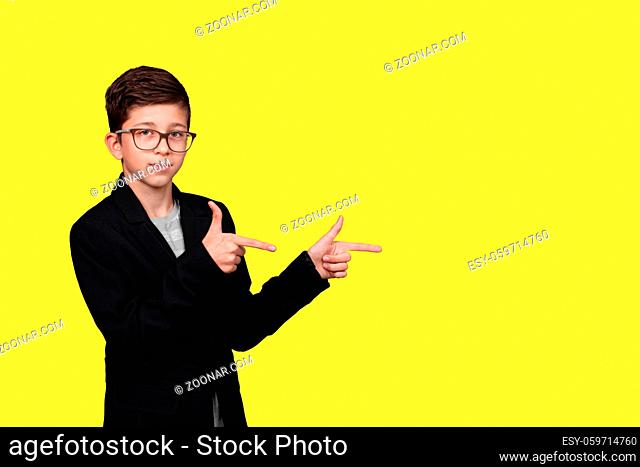 cute boy pointing his hands to empty place isolated on yellow background. copy space