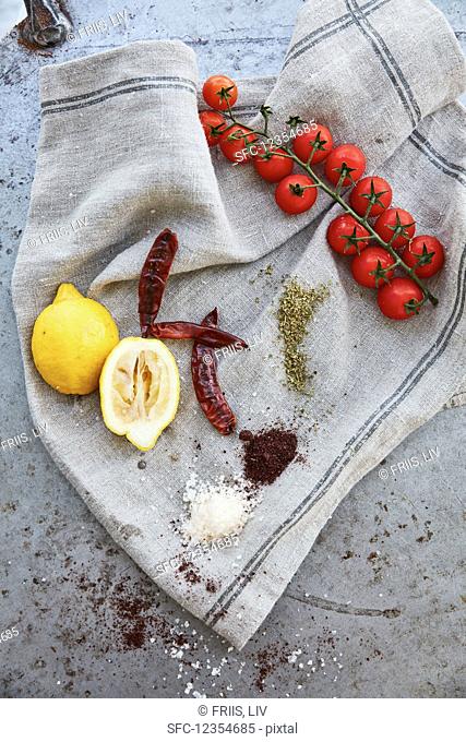 Lemons, tomatoes, chillies, and spices on a linen cloth