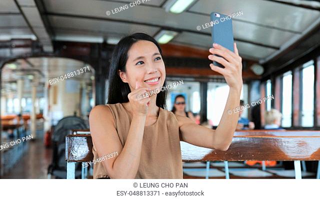 Woman taking selfie with cellphone on ferry in Hong Kong