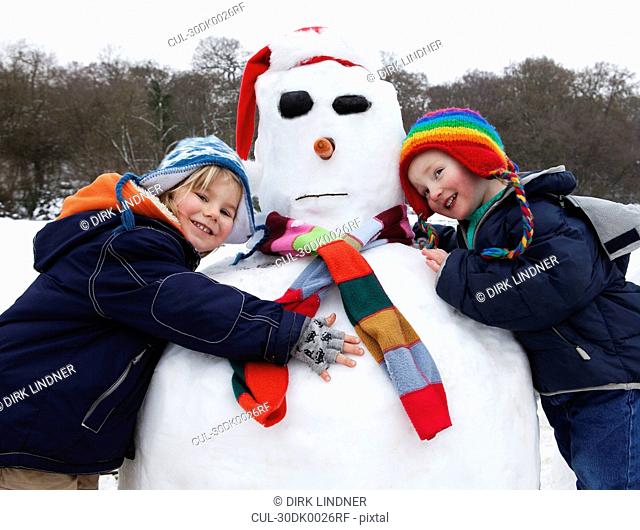 Two boys hugging a snowman