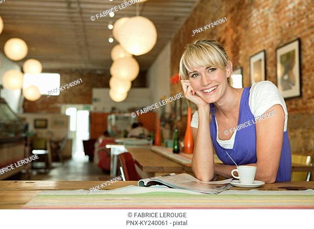 Woman reading a magazine and drinking coffee in a cafe