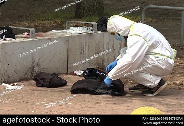 06 June 2022, Lower Saxony, Hanover: A police officer examines objects left behind at the scene after a 33-year-old man was seriously injured by knife wounds...