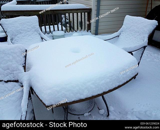 half a foot of white snow on table and chairs