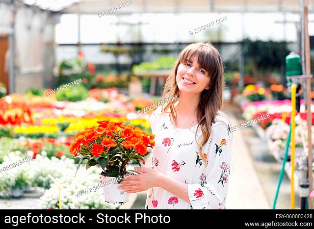 Young woman buying flowers at a garden center. selects bright colorful potted plants flowers. Flowers in pot in fertilized soil