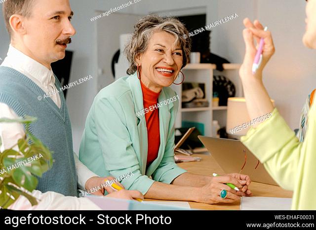 Woman in bright clothes talks with colleagues, having fun at the studio