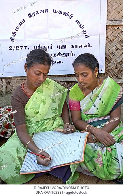 Ladies volunteers of NGO Chinmaya Organization of Rural Development CORD maintaining account book of contribution of Micro Credit Finance ; Siruvani ; Karnataka...