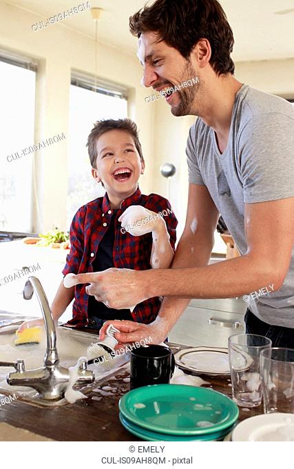 Father and son with soap suds on hands